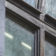 Close view of a weathered metal window frame where a vertical mullion meets a horizontal rail.